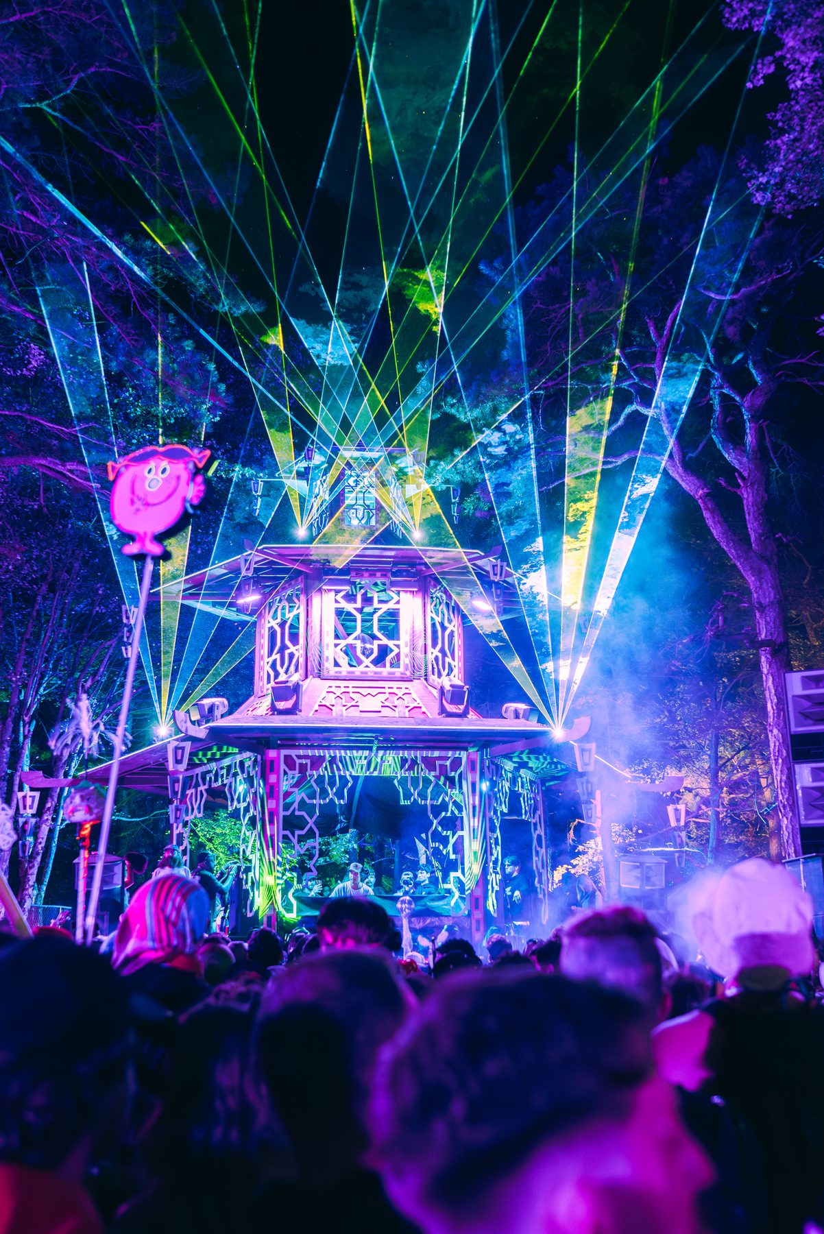 Festival art stage lit in purple with lasers over the crowd