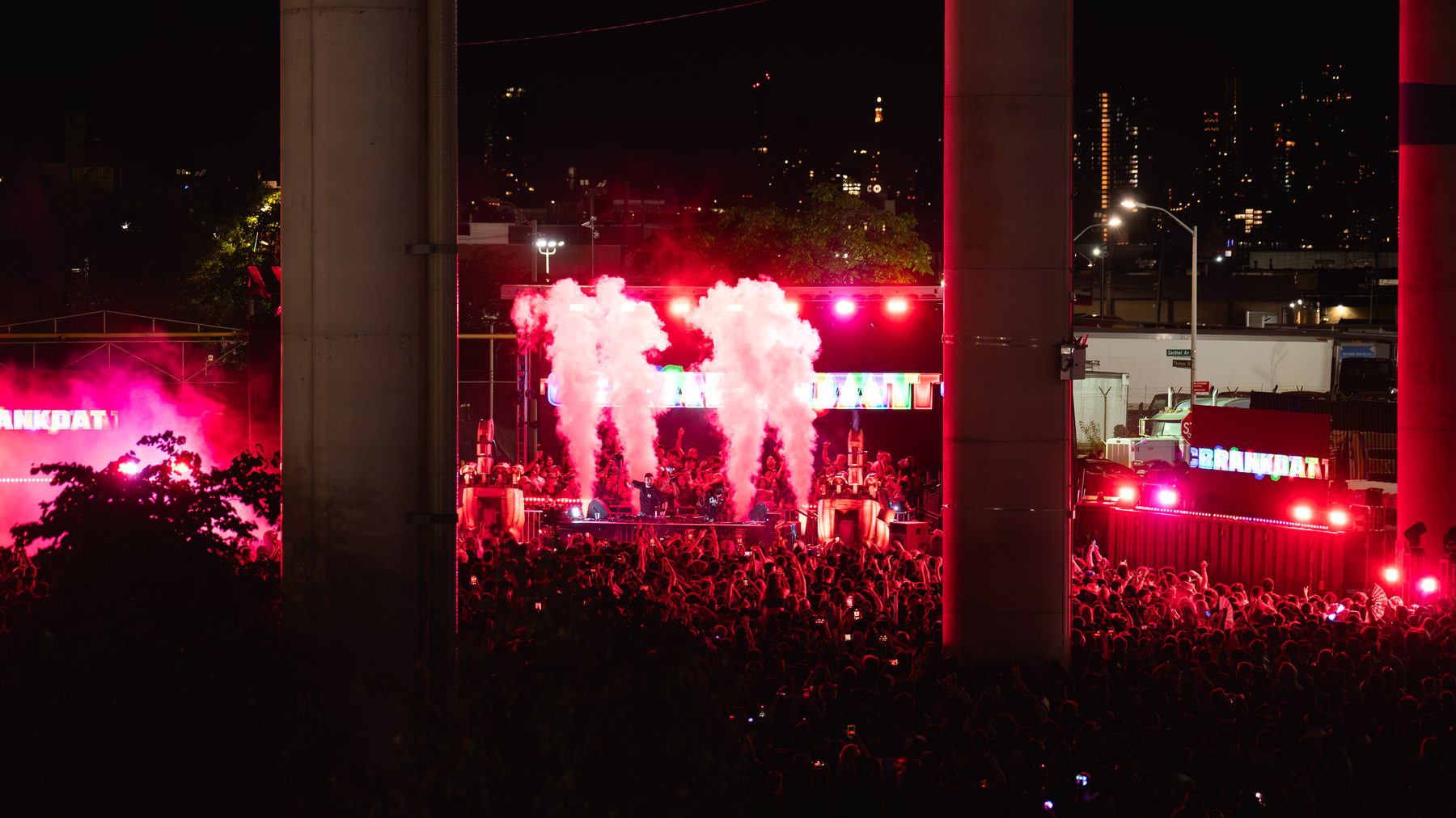 Outdoor stage at Under The K Bridge with CO2 jets and red lighting under the bridge